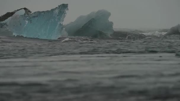 Elmas sahilindeki buzdağlarının üzerinde dalgalar kırılıyor. — Stok video
