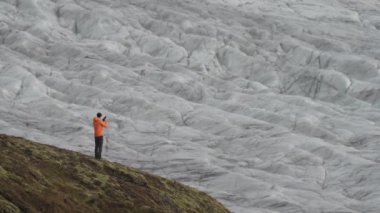 Büyük bir buzulun fotoğrafını çeken tanınmamış bir turist.