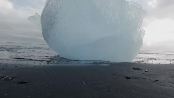 Iceberg azul profundo sobre la arena negra en slow-mo — Vídeos de Stock
