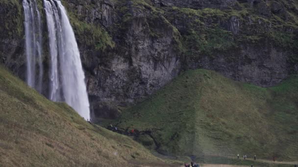 Seljalandsfoss waterfall in slow motion with unrecognizable tourist — Stock Video