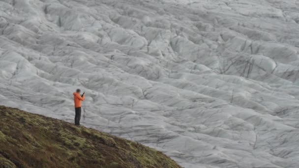 Pixelerad turist bakifrån ta bilder av massiv glaciär — Stockvideo