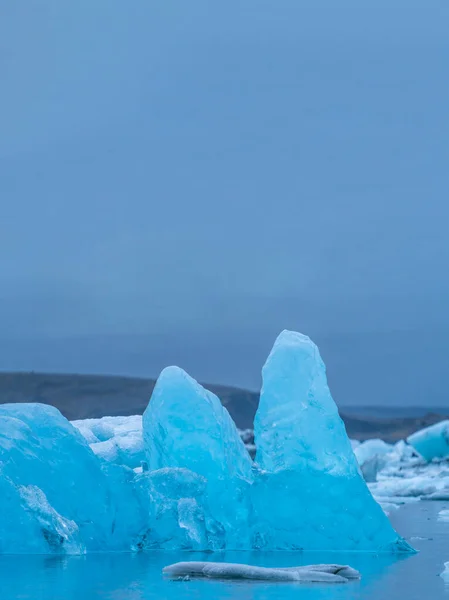 Masywne szczyty góry lodowej na lagunie Jokulsarlon pod bezchmurnym niebem — Zdjęcie stockowe