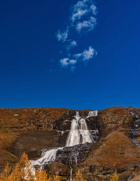 Long exposure of waterfall gliding over the rocks under small clouds — Stock Photo, Image