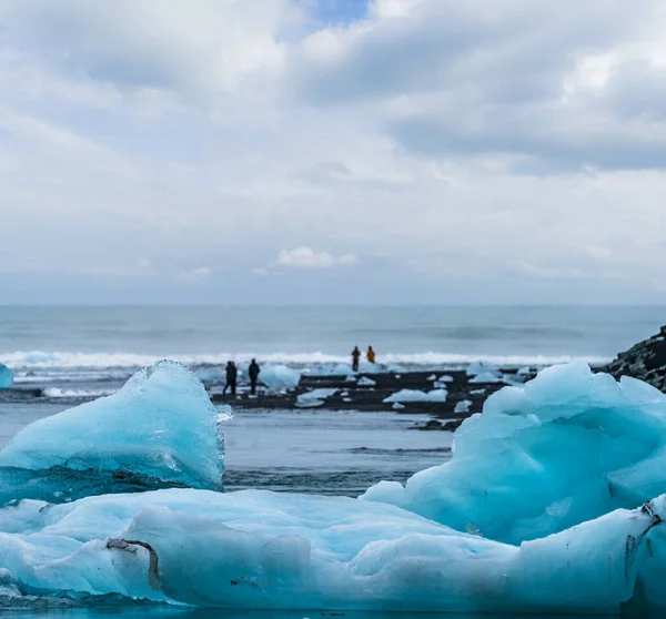 Zamazani turyści robiący zdjęcia nad czarną plażą, Jokulsarlon — Zdjęcie stockowe