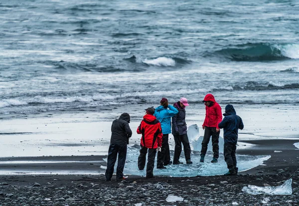 Tanımlanamayan turistler elmas plajında buzdağının üzerinden fotoğraf çekiyorlar. — Stok fotoğraf