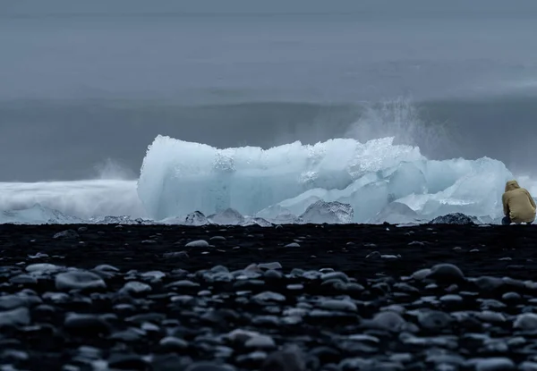 Icebergs azules sobre la playa de arena negra con turista — Foto de Stock