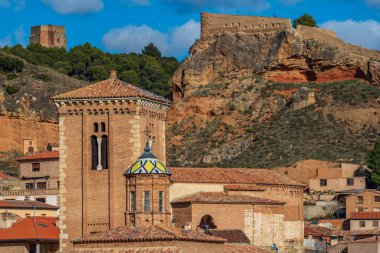 Arka planda renkli kiremit çatılı ve şatosu olan eski bir kule.