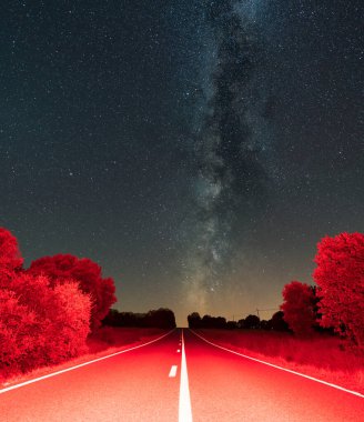 Straight red road with white lines under the milky way