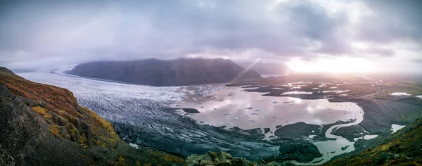 Spettacolare panorama su un massiccio ghiacciaio con nuvole e raggi luminosi Foto Stock Royalty Free