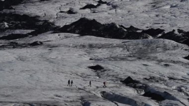 Büyük bir buzulun üzerinde yürüyen tanınmayan turist grubu profili