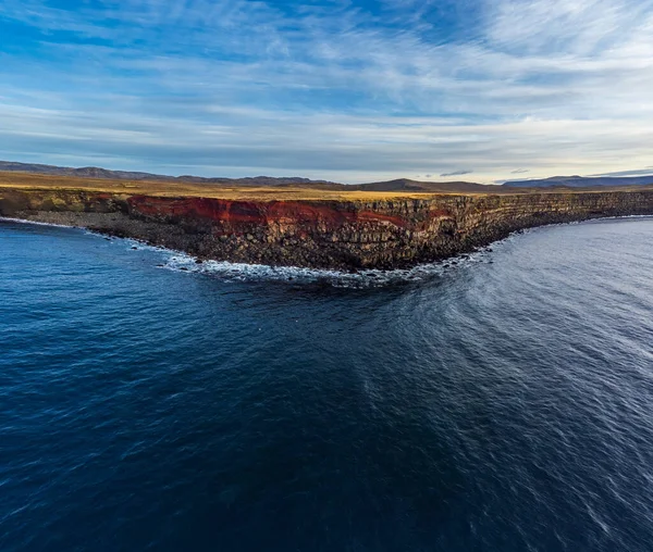 アイスランドの赤い縫い目と火山の急な崖の海からの広い角度のビュー — ストック写真