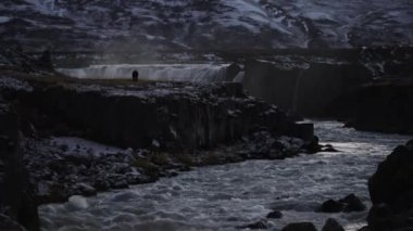 Alacakaranlıkta turistlerle dolu Godafoss şelalesi.