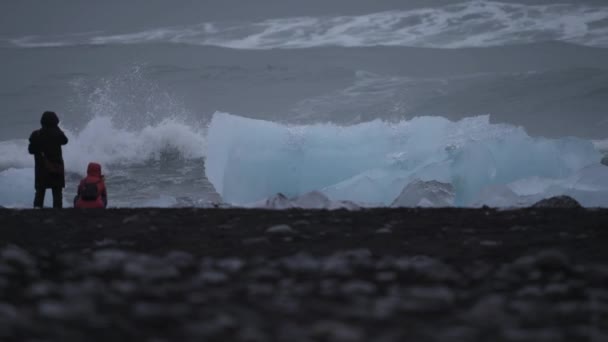 Waves Breaking Icebergs Black Sand Beach Tourists Taking Photos — стоковое видео