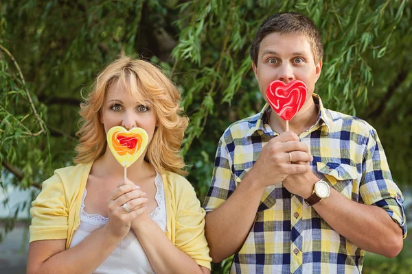 Pareja sosteniendo piruletas en forma de corazón — Foto de Stock