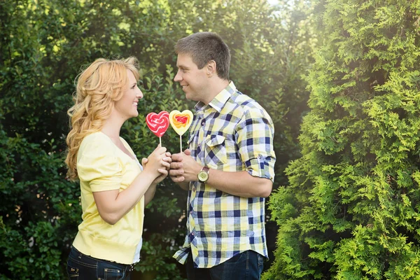 Casal segurando pirulitos em forma de coração — Fotografia de Stock