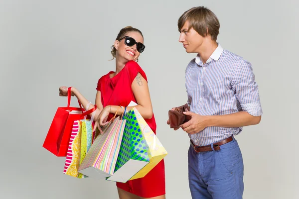 Young couple with many bags and empty wallet — Stock Photo, Image