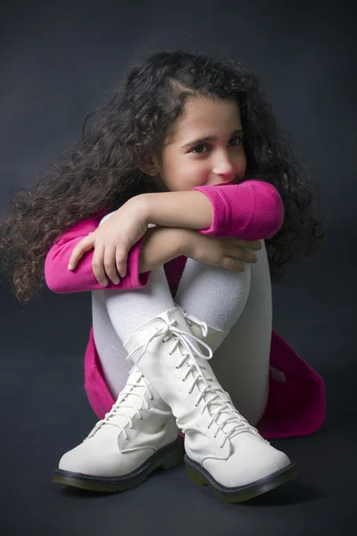 Pretty little girl sitting on the floor in white boots — Stock Photo, Image