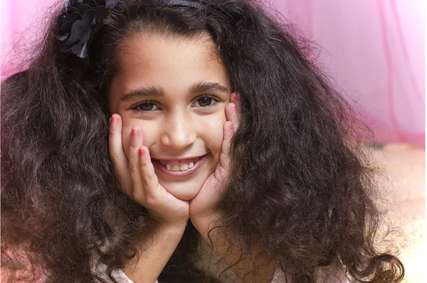 Little cute swarthy brunette girl is on the fur carpet on pink — Stock Photo, Image