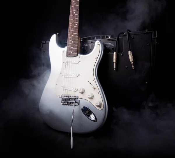 黑色背景下烟雾弥漫的银电吉他和吉他放大器 — 图库照片