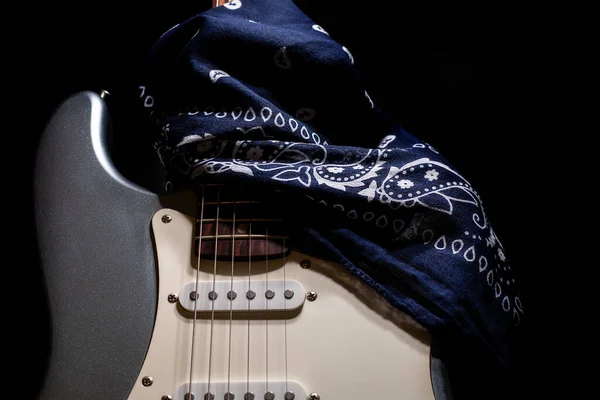 Guitare électrique argentée avec bandana bleu isolé sur fond noir. — Photo