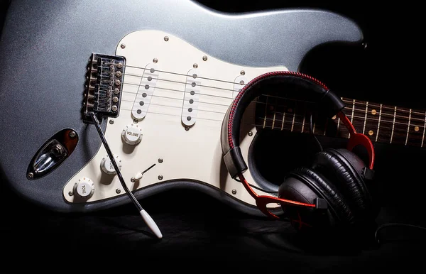 Guitare électrique argentée avec écouteurs isolés sur fond noir — Photo