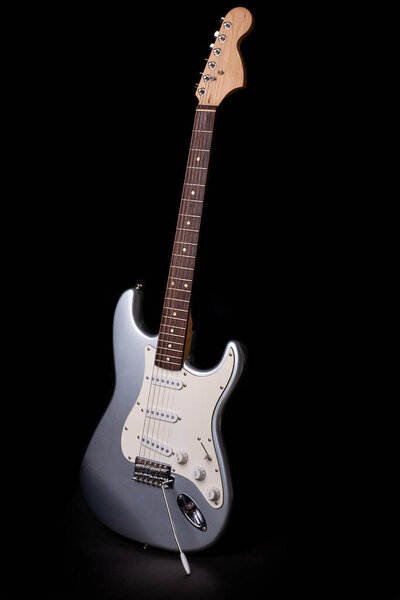 Silver electric guitar isolated on black background.