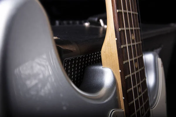 Silberne E-Gitarre und Gitarrenverstärker auf schwarzem Hintergrund. — Stockfoto