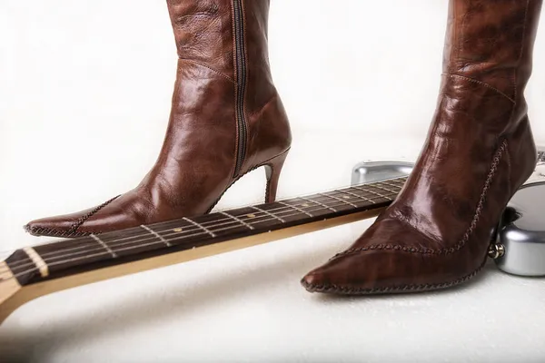 Silver electric guitar and brown womens high heels boots — Stock Photo, Image
