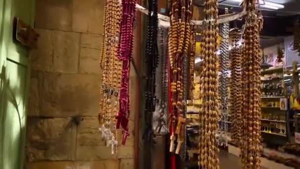 Les touristes visitent la rue du marché du bazar dans la vieille ville de Jérusalem, chapelet dans un magasin. — Video