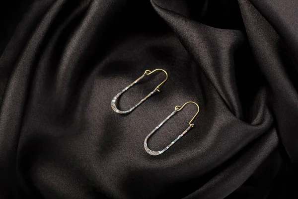 Metal Earrings Black Silk Background — Zdjęcie stockowe