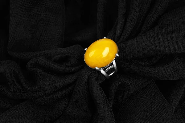 Srebrny pierścień z chińskim bursztynem na czarnym tle tkaniny. — Zdjęcie stockowe
