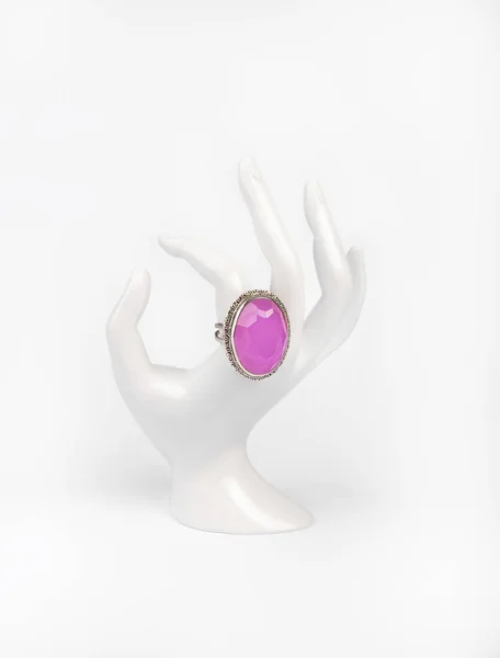 Mano blanca de plástico con anillo de plata y cuarzo rosa sobre fondo blanco. —  Fotos de Stock
