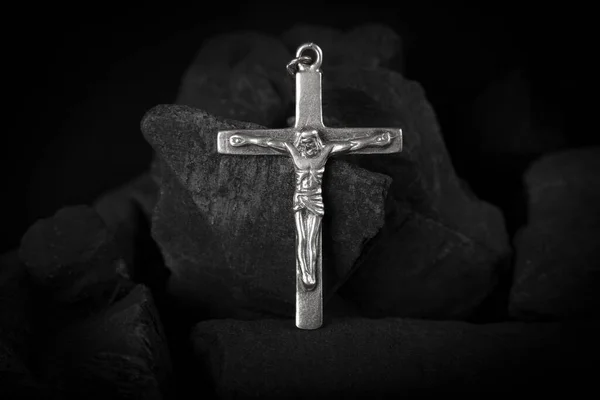 Silver crucifix necklace cross on pieces of coal.. Royalty Free Stock Images