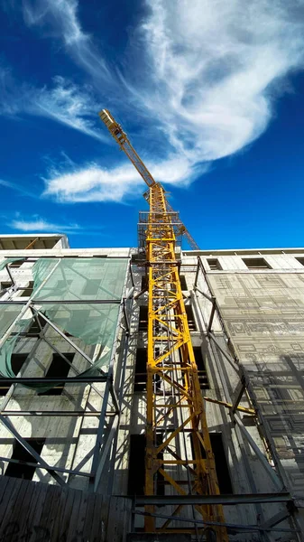 Tower building crane against the blue sky and sun. Construction of new buildings with a crane. Tower crane in Tbilisi, Georgia