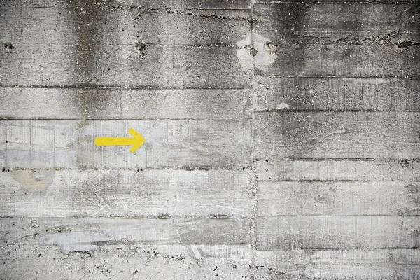 Yellow arrow on cement wall — Stock Photo, Image