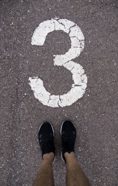 Detail of feet above the number three on a running track
