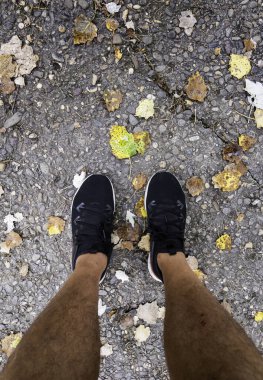 Soğuk bir sonbahar gününde genç bir adamın ayaklarının ayrıntıları.