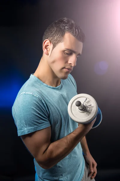 Lihaksikas nuori mies käsipainoilla — kuvapankkivalokuva