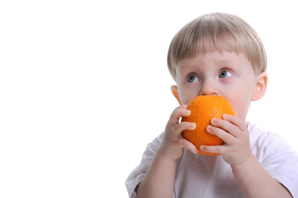 Хлопчик їсть помаранчевий — стокове фото
