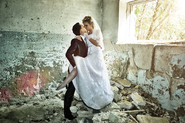 Nygifte par kysser i en kastet bygning – stockfoto