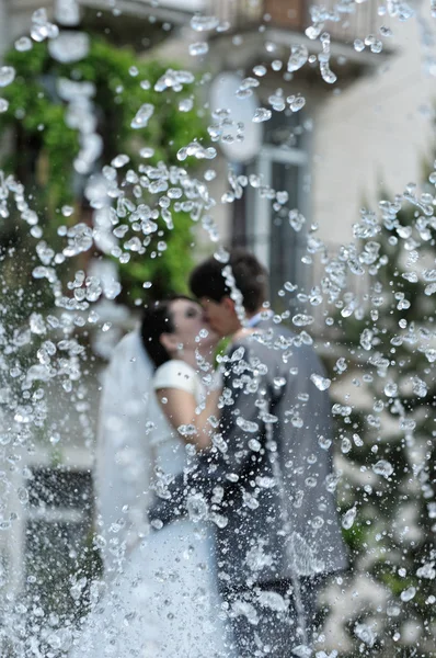 Beso de boda en el parque con una fuente — Foto de Stock