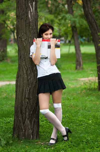 Estudante de pé perto de uma árvore com um livro em um parque de verão — Fotografia de Stock