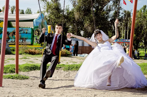 Happy bride and groom on swing at wedding day — Stock Photo, Image