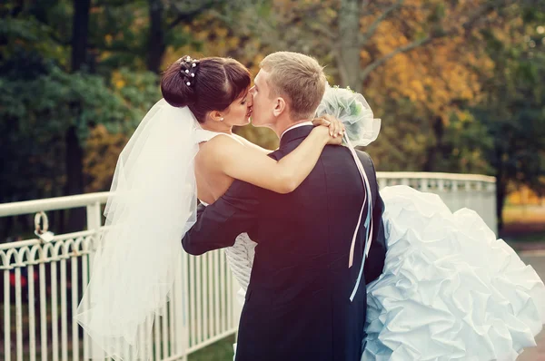 Щаслива щойно одружена пара цілується на маленькому мосту — стокове фото