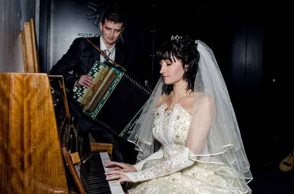 Bride playing the piano and groom playing the accordion — Stock Photo, Image