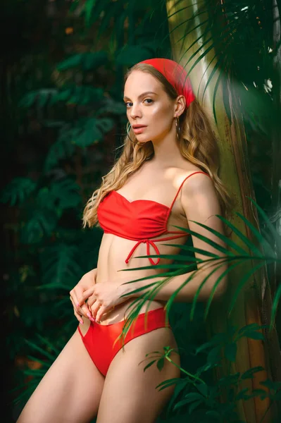 穿着红色泳衣的性感金发女人在绿色热带森林里 — 图库照片