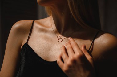 Genç ve çekici bir kızın boynunda iki yüzük olan altın zincir.