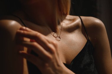 Genç ve çekici bir kızın boynunda iki yüzük olan altın zincir.