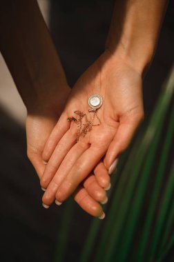 Değerli yuvarlak kolye narin kadın ellerinde.