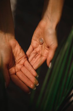 Değerli yuvarlak kolye narin kadın ellerinde.